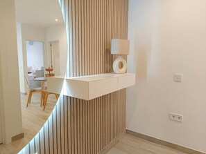 Ein modernes Interieur mit einer weißen Konsole, einer Lampe und einer Wand mit Holzverkleidung.
