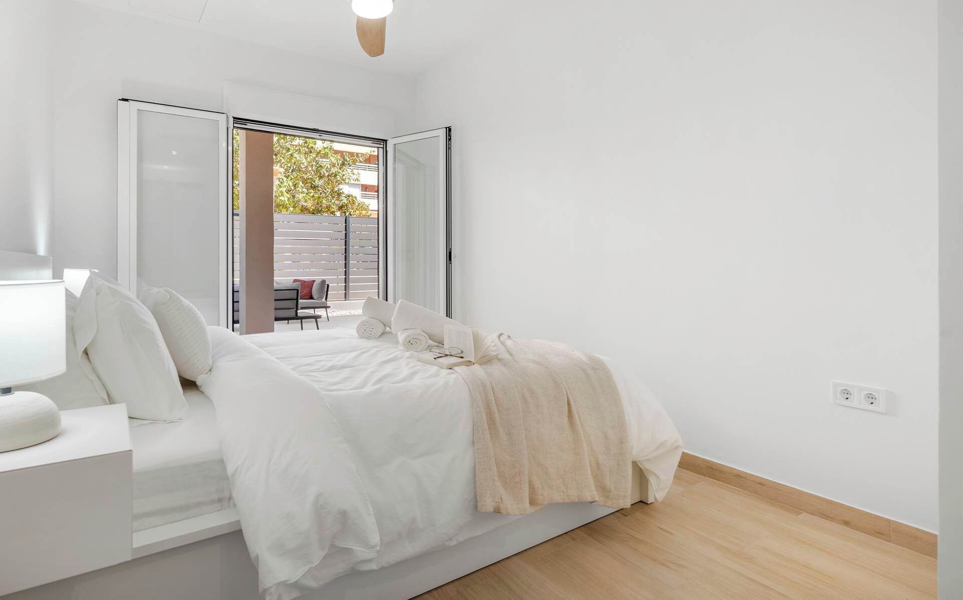 Une chambre à coucher moderne, avec un lit, une table de chevet et une vue sur un espace extérieur grâce à une porte coulissante.