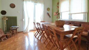 Un comedor con mesa de madera, sillas, un radiador y una ventana con persianas.