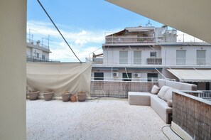 A rooftop terrace with a sofa, potted plants, and a view of buildings. - Great View Kolonaki Lycabettus (Athens)