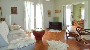 Una sala de estar con un sofá, un televisor, un tambor y un comedor con sillas.