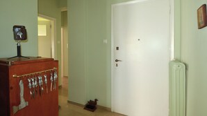 Un pasillo con una puerta blanca, un armario de madera con herramientas y un radiador.