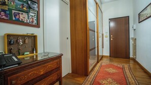 A hallway with a wooden desk, keys, a bulletin board, a patterned rug, and a door. - San Siro Suite – Elegant Room Near San Siro (With Host) (Milan)