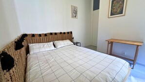 A bed with a woven headboard, a bedside table, and a small nightstand. - San Siro Suite – Elegant Room Near San Siro (With Host) (Milan)