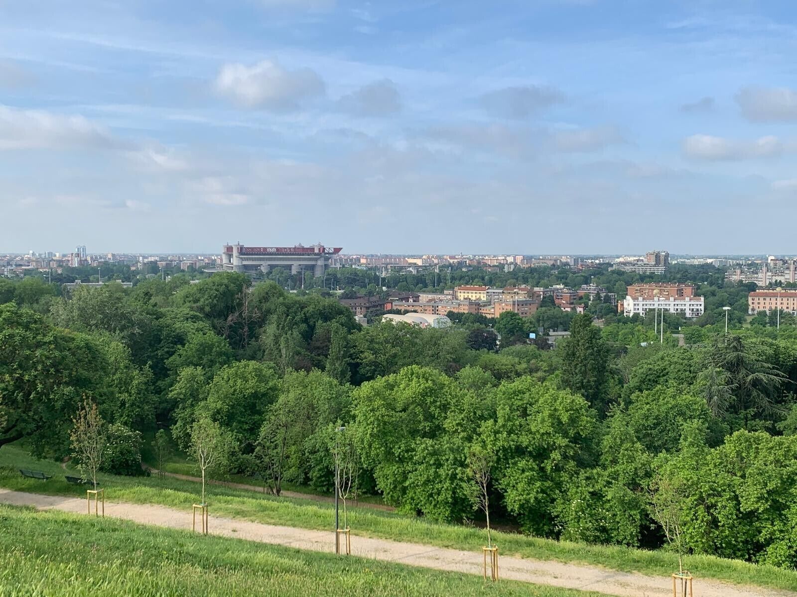 Eine Stadtansicht mit einem markanten Gebäude in der Ferne, umgeben von Grünflächen und einem klaren Himmel.