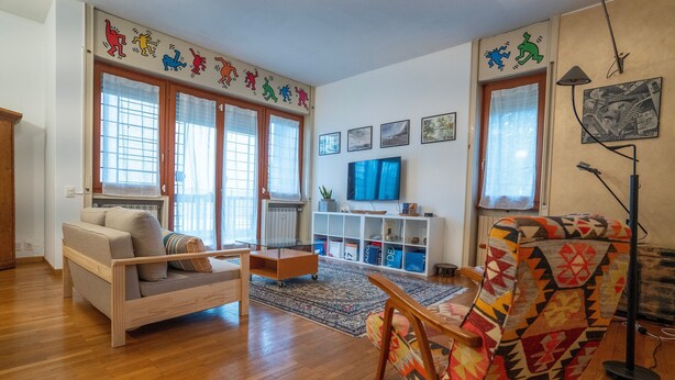 A living room with a sofa, armchair, TV, and a bookshelf. - San Siro Suite – Elegant Room Near San Siro (With Host) (Milan)