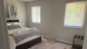 A bedroom with a bed, two windows, a radiator, and a door. - This beautiful 3-bedroom condo in Painesville has the comforts of home, elevated (Painesville)