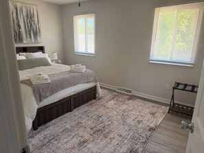 A bedroom with a bed, two windows, a radiator, and a door. - This beautiful 3-bedroom condo in Painesville has the comforts of home, elevated (Painesville)