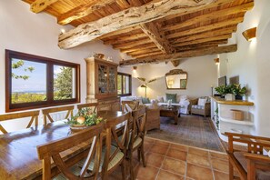 A rustic interior with a wooden dining table, chairs, a large cabinet, and a view through a window. - 5-bedroom Villa Near Southwest Beaches (Sant Antoni de Portmany)