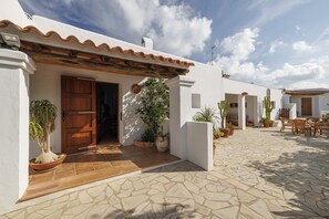 A courtyard with a tiled floor, a wooden door, and potted plants. - 5-bedroom Villa Near Southwest Beaches (Sant Antoni de Portmany)