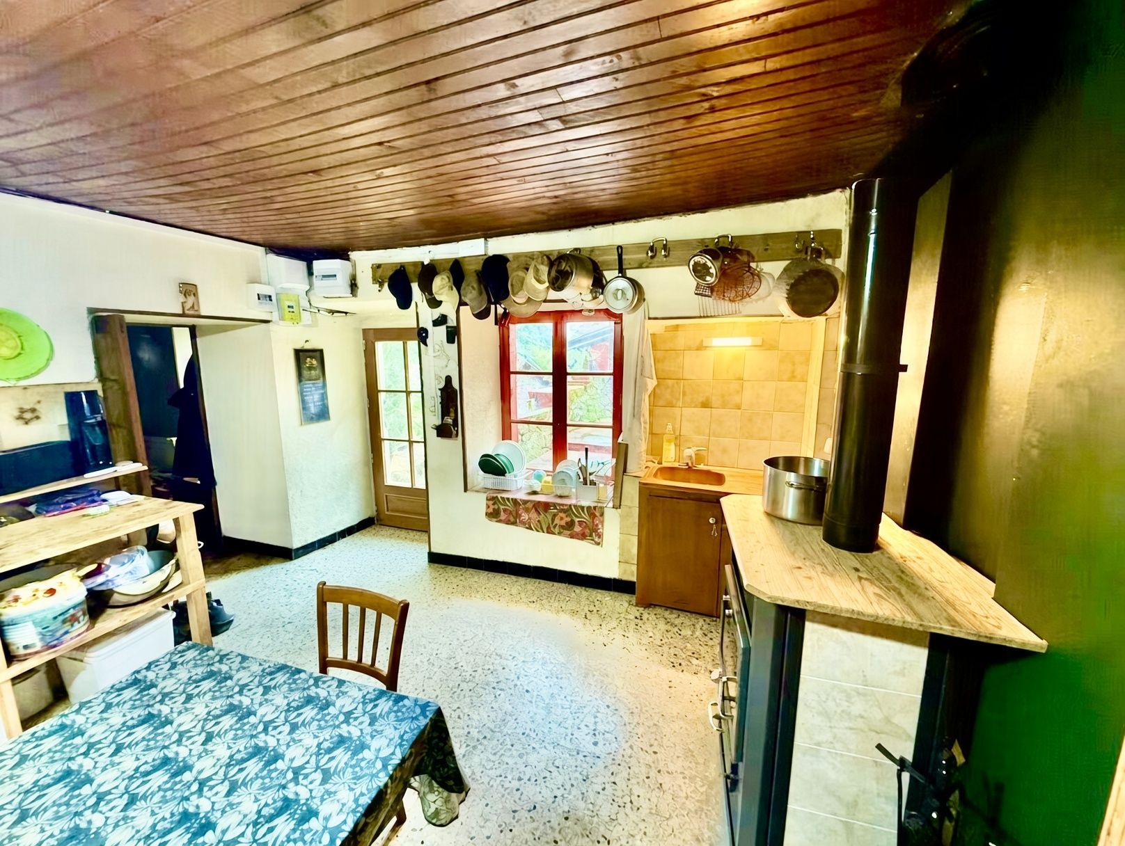 Une cuisine compacte avec un plafond en bois, un coin repas avec une table et des chaises, et une petite fenêtre donnant sur un paysage agréable.
