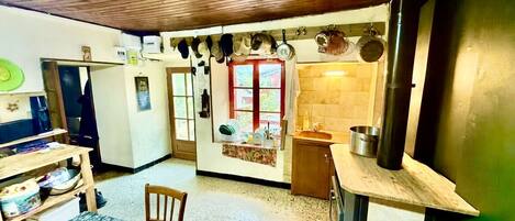 Cocina compacta con techo de madera, comedor con mesa y sillas, y una ventana pequeña con vistas.