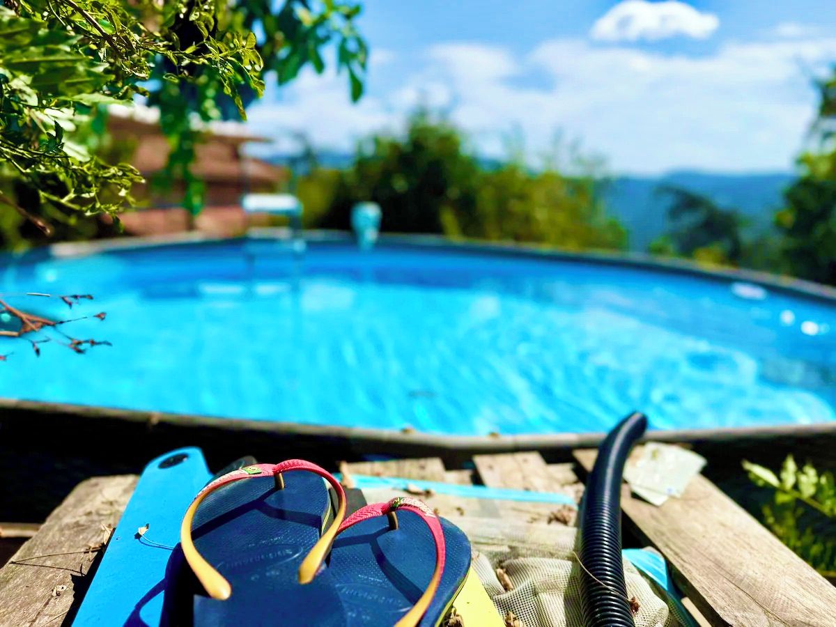 A poolside area with a lounge chair, flip-flops, and a pool hose.