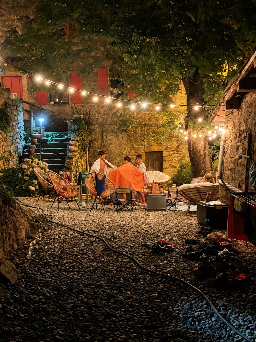 An outdoor seating area with stone walls, string lights, and wicker furniture.