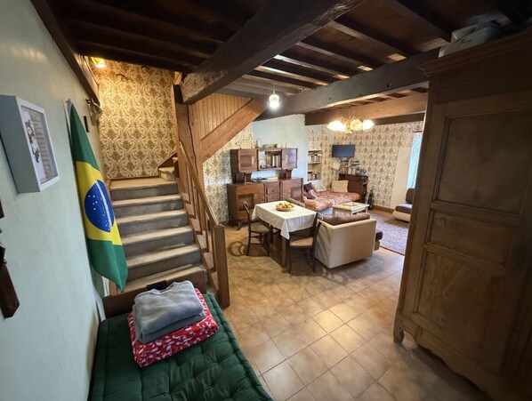 Eine Treppe führt zu einem Essbereich mit Tisch und Stühlen, einem Sofa und einer Flagge an der Wand.