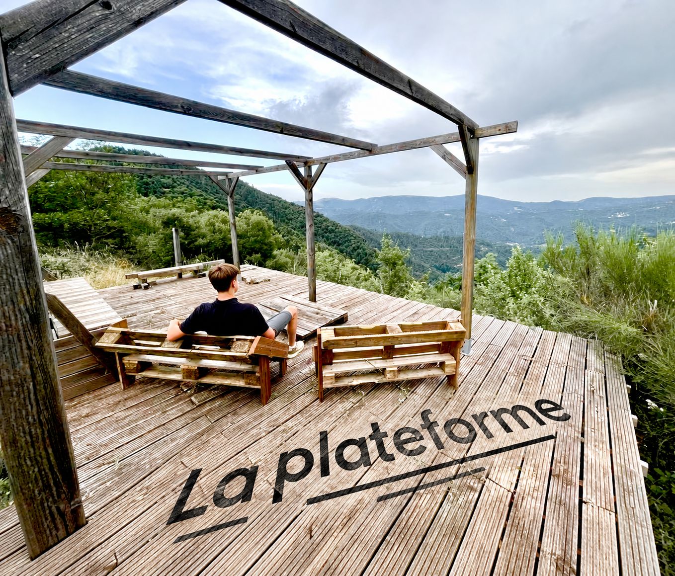 A wooden deck with benches and a person sitting. The deck has 'La plateforme' written on it.