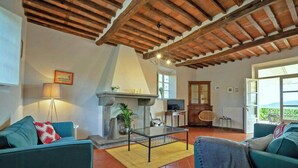 Un salon avec une cheminée, deux canapés, une table basse et un téléviseur.