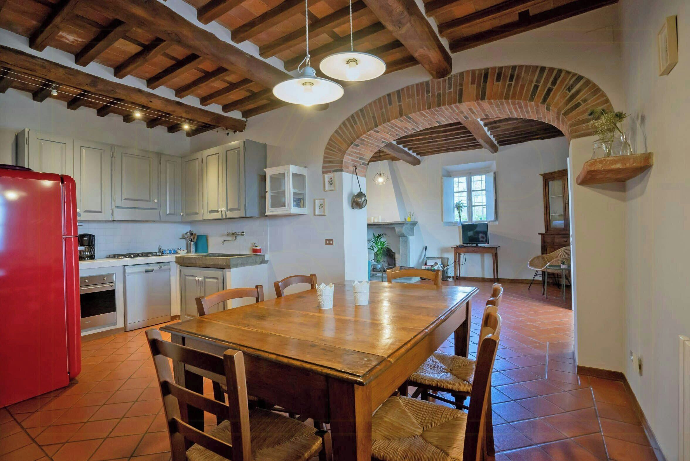 A kitchen with a wooden table, chairs, and a red refrigerator.