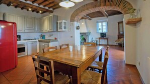 Une cuisine avec une table en bois, des chaises et un réfrigérateur rouge.
