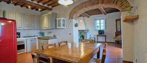 A kitchen with a wooden table, chairs, and a red refrigerator.
