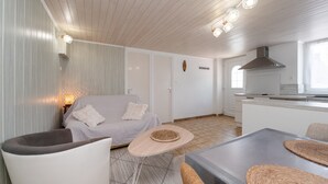 A modern kitchen with a stove, a dining table with chairs, a sofa, and a small rug.