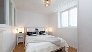 A bedroom with a large bed, bedside tables, a window with curtains, and a ceiling light fixture.