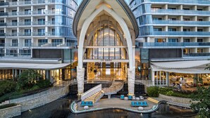 Un hotel moderno con un atrio central, varios pisos y un área de piscina.