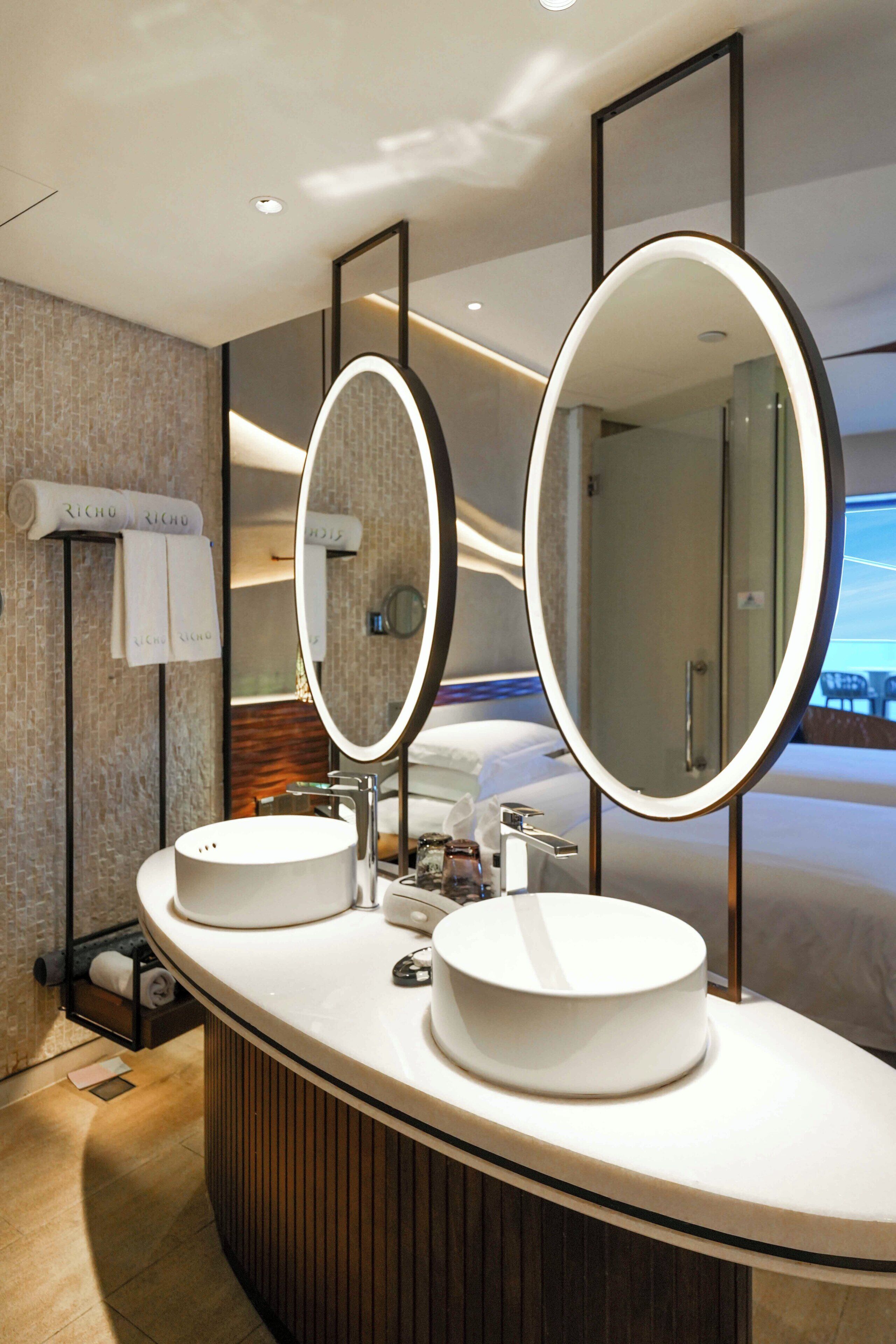 Un baño moderno con dos lavamanos, un espejo grande y un perchero con toallas.