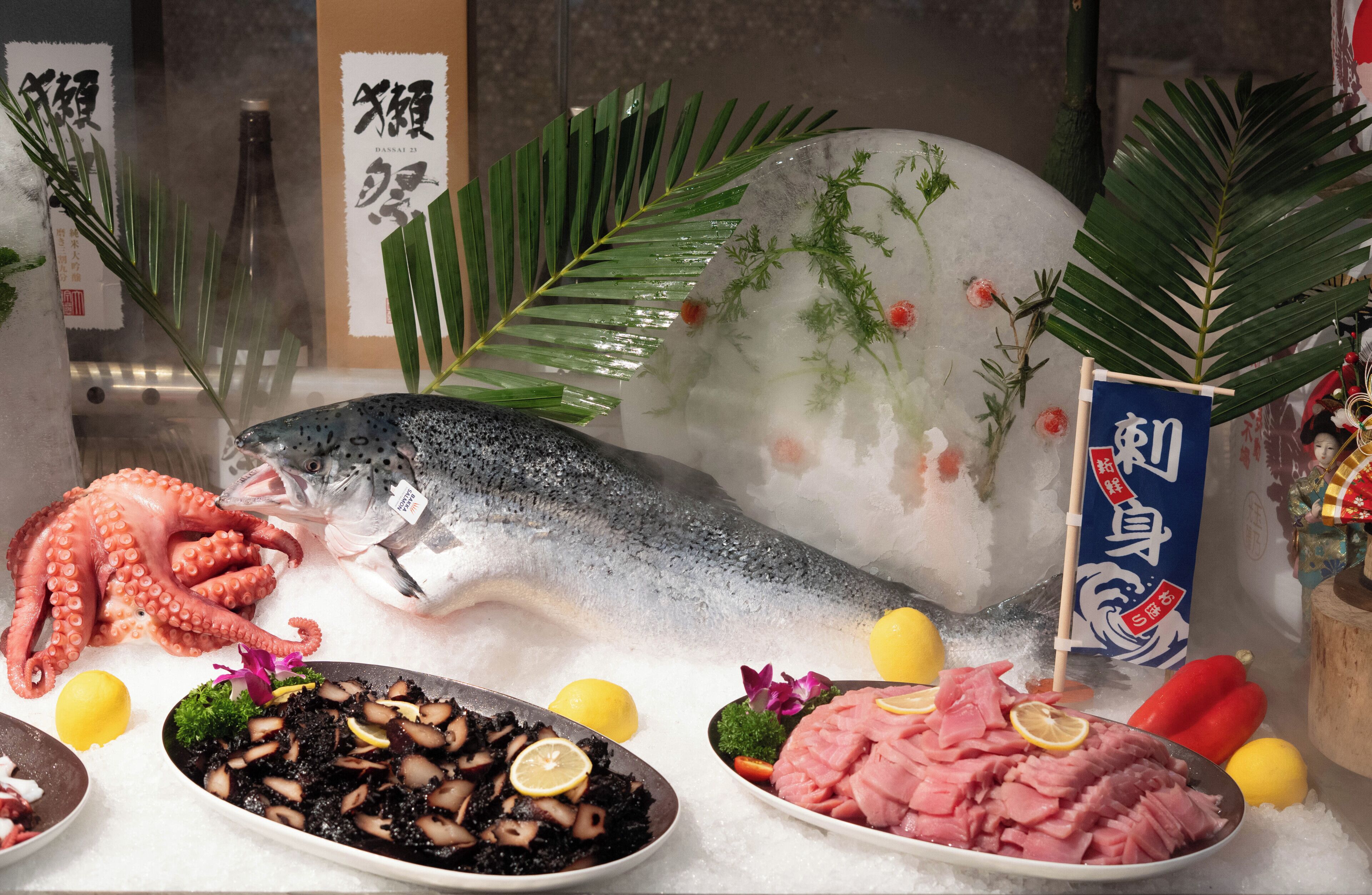 Un présentoir de fruits de mer avec un gros poisson, un poulpe et divers plats.
