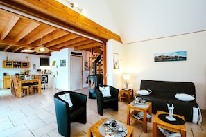 Un salon comprenant un canapé, des fauteuils, une table basse, une cheminée et un coin repas avec une table et des chaises.