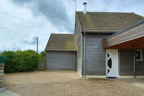 Un bâtiment à deux étages, doté d’un toit recouvert de tuiles, d’une porte de garage et d’un petit porche.