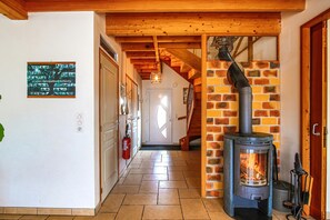 A hallway with a wood-burning stove, a fire extinguisher, and a staircase leading to another room. - Eco-friendly holiday home at the gateway to the marshlands! (Carentan-les-Marais)
