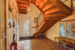 Eine Treppe mit Holzbalken, ein Feuerlöscher, eine Karte an der Wand und eine Tür mit Spiegel.
