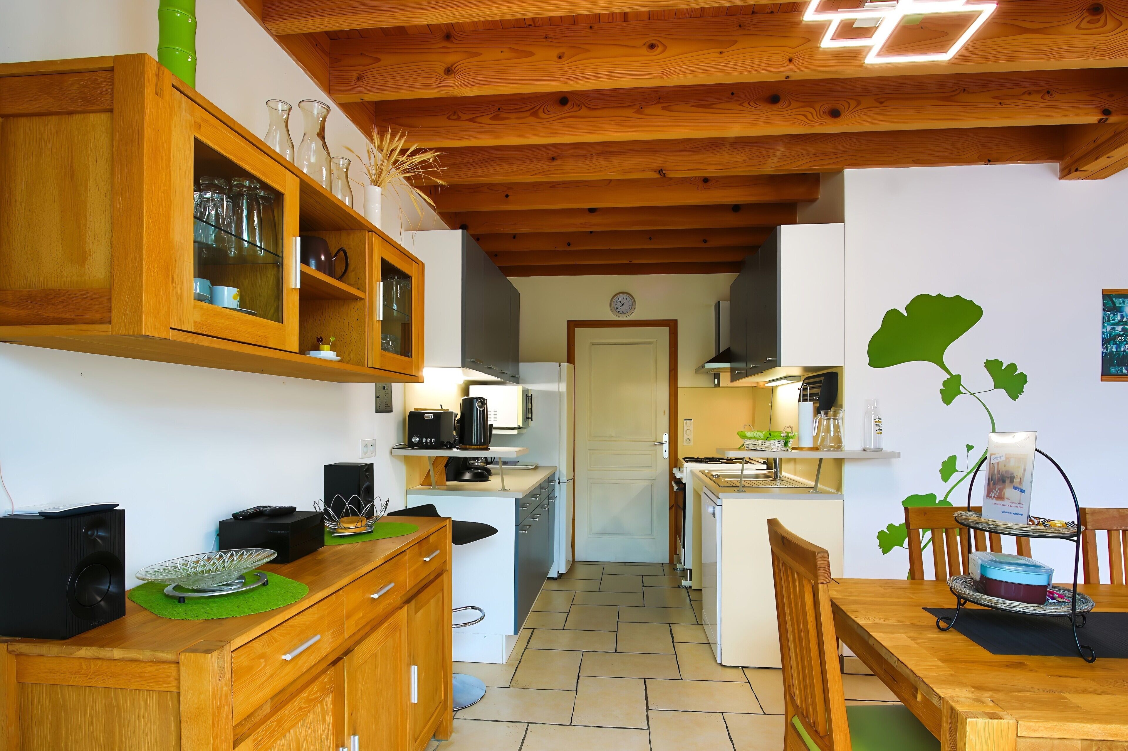 Une cuisine compacte dotée de meubles en bois, d’une machine à café et d’un coin repas avec une table et des chaises.