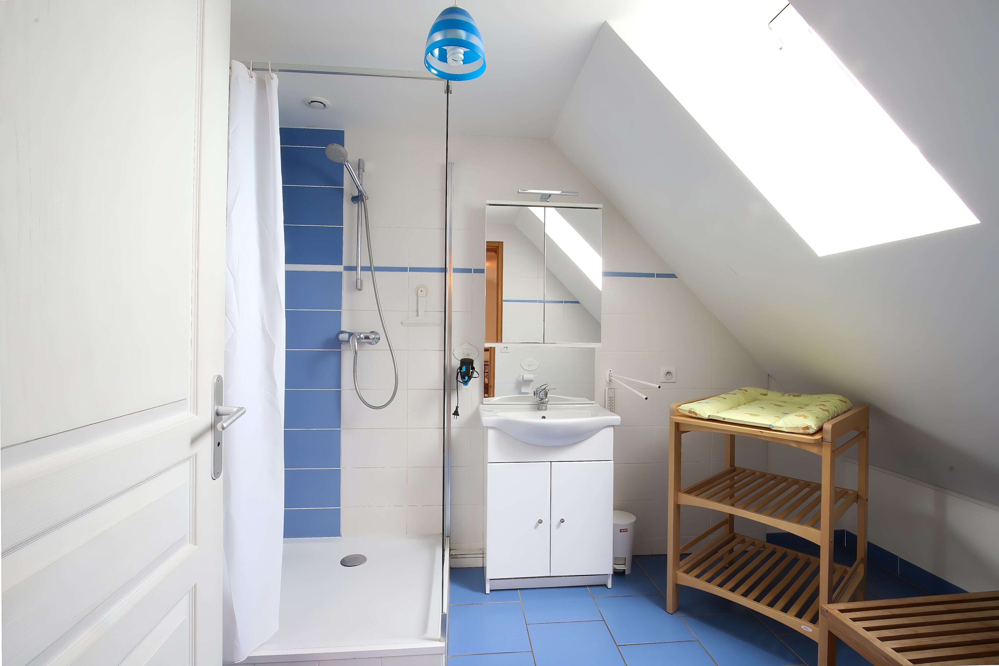 Un bany amb dutxa, un lavabo i una prestatgeria de fusta.