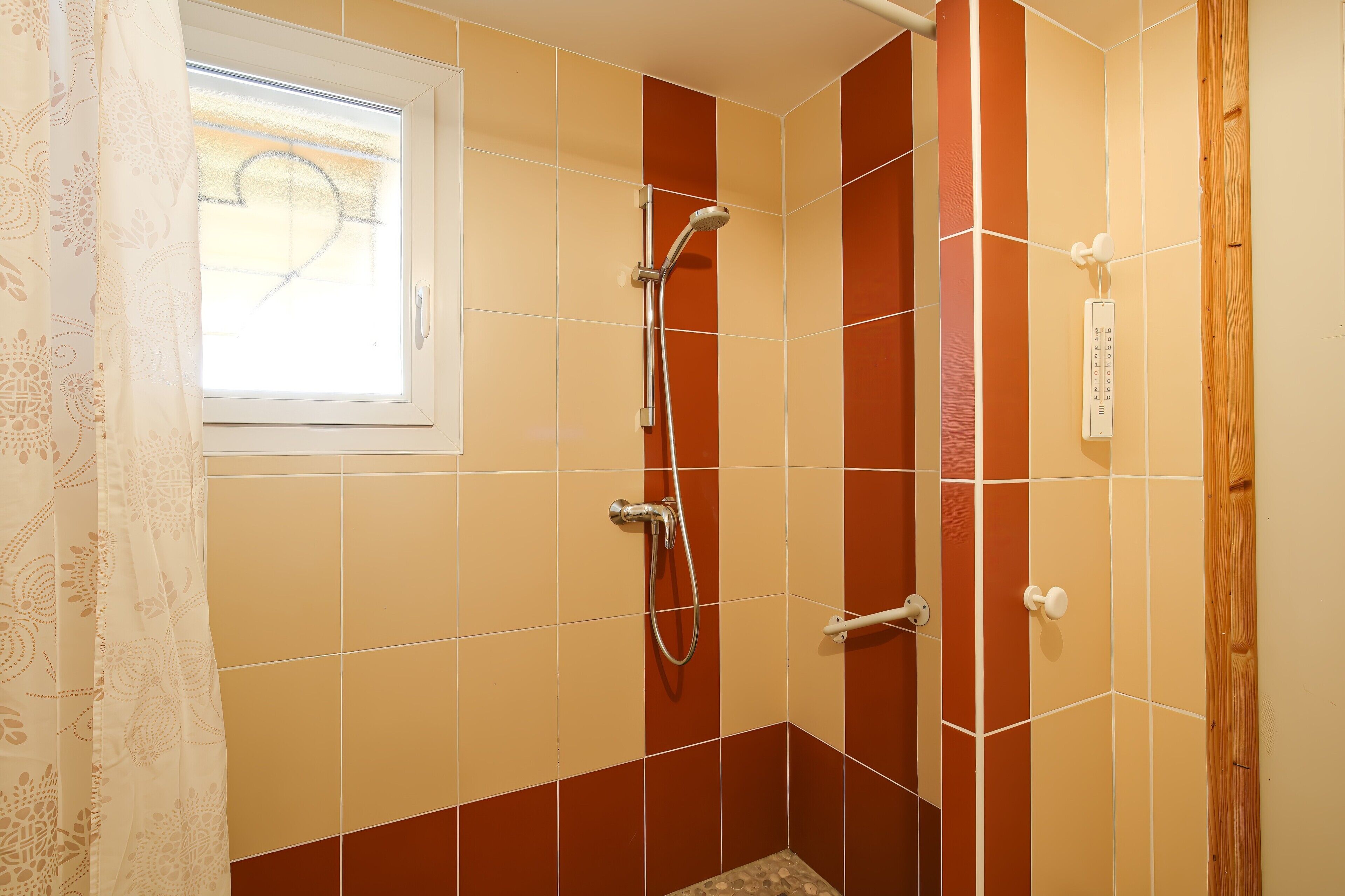 Dusche mit Handbrause, ein Fenster mit Blick und ein Bedienfeld.