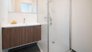 A bathroom with a glass shower enclosure, a wooden vanity, and a white sink. - Opera Square Family Apartment for 10 Guests (Antwerp)