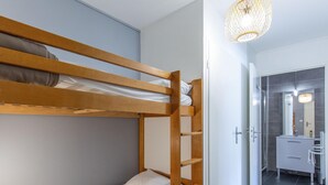A bunk bed with a wooden ladder, a white door, and a bathroom with a mirror and sink. - 6-guest Rental With Dedicated Ski Locker (Germ)