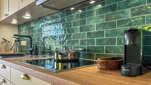 Une cuisine moderne avec un revêtement mural vert, des appareils électroménagers en acier inoxydable et des meubles de cuisine en bois.