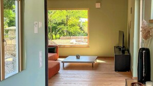 Un intérieur moderne avec un plafond en bois, un coin repas, un canapé et une vue sur la verdure à l’extérieur.