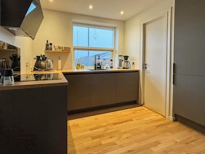 Een moderne keuken met een raam, houten vloer en een inbouwoven.