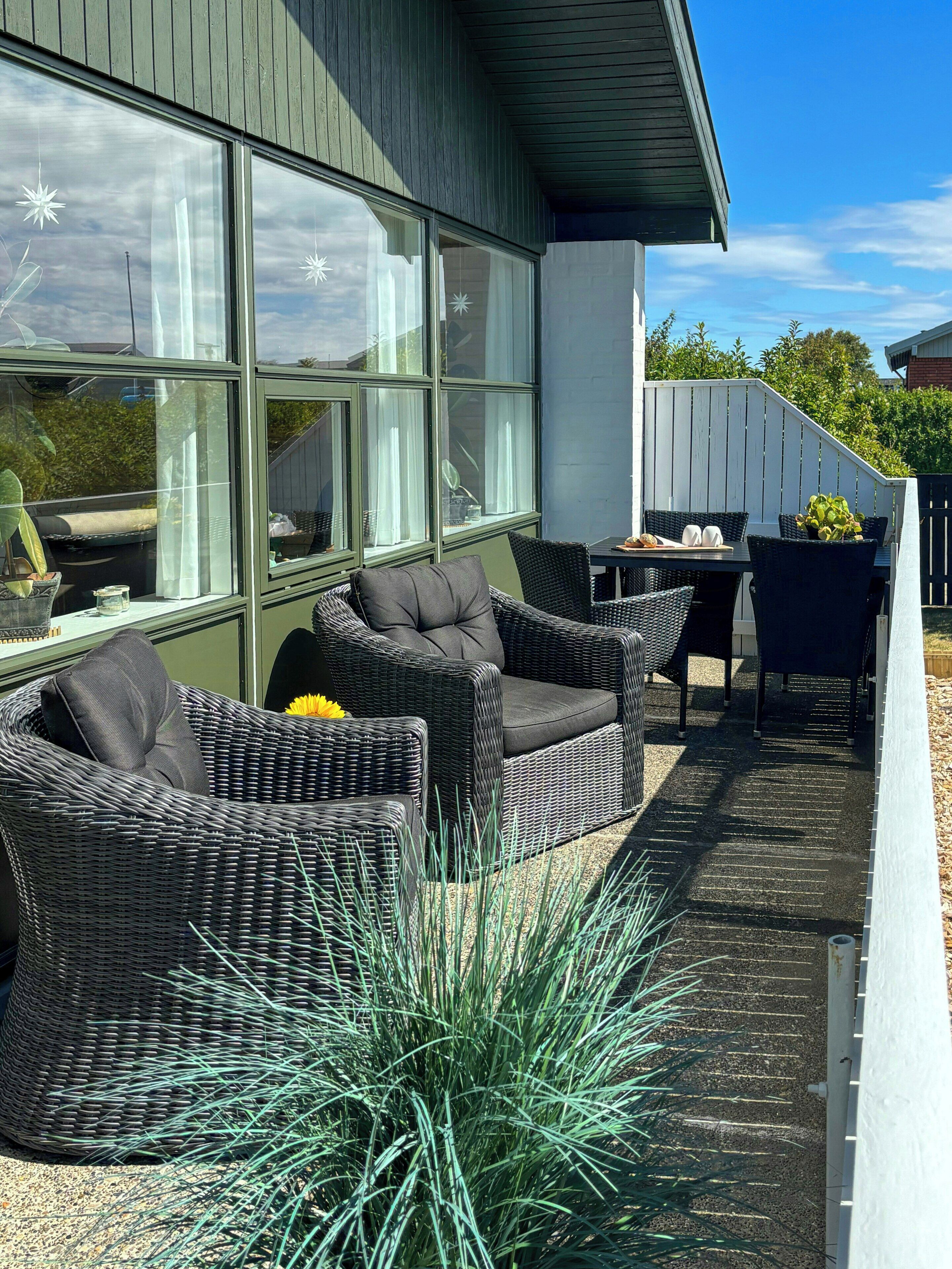 Een terras met rieten meubels, een tafel en een potplant.