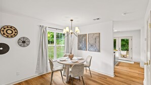A dining area with a round table, chairs, a chandelier, and artwork on the walls. - Urban Oasis in Charotte (Charlotte)