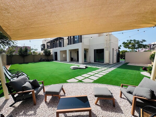 A modern outdoor patio with a seating area, a well-maintained lawn, and a contemporary building in the background.