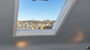 Et ovenlysvindue med udsigt over en by, inklusive en markant kirke og boligbygninger.