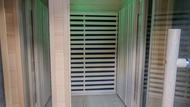 Et sauna-rum med digital timer, trælameller og en bænk.