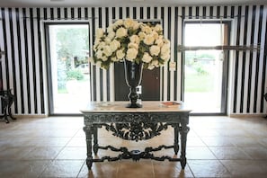 A room with a large vase of flowers on a table, a door with a view, and striped walls. - Villa with pool in the heart of Puglia (San Michele salentino)