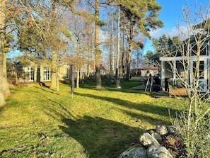 A residential property with a grassy yard, trees, and a house with a red roof. - Cottage near golf course and nature reserve in När (Stånga)