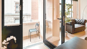 Ein modernes Apartment mit Balkon, einem Ledersofa, einem Esstisch und einem Blumentopf.