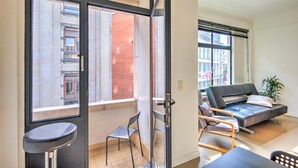 Eine moderne Wohnung mit Balkon, Sofa, Sessel und einem kleinen Tisch.